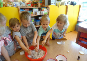 Dzieci mieszają łyżkami sól z płatkami kwiatów w misce.